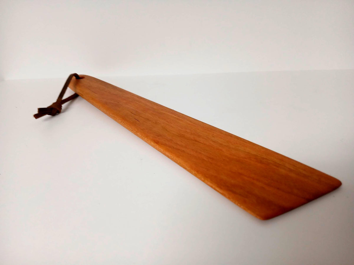 Cherry Flat Spatula shown at an angle. Finished with beeswax and tied with a leather strand for hanging