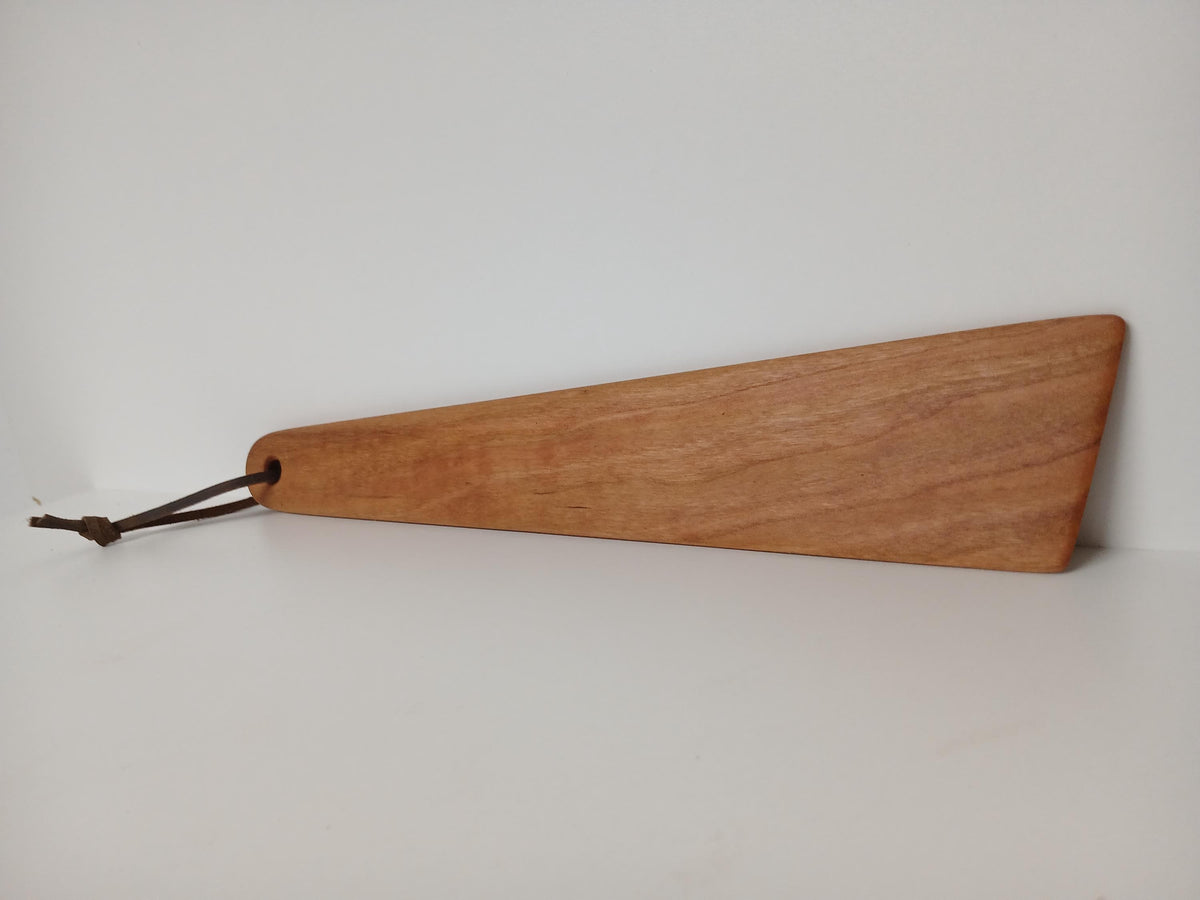 Cherry Wood Turner or Flat Spatula finished with natural oil shown on the side view, tied with a leather hanging strand