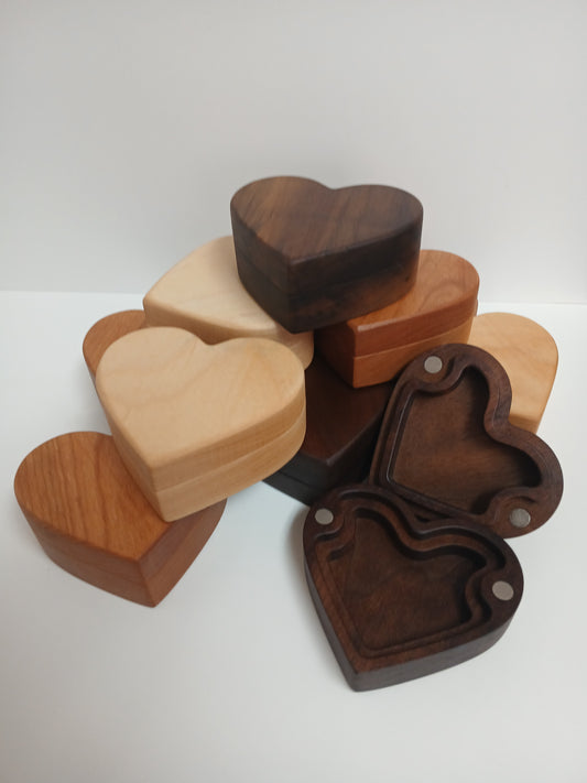 A collection of heart-shaped wooden keepsake boxes in various wood tones, including dark walnut, hard maple, alder wood, and cherry. All placed with a white background.