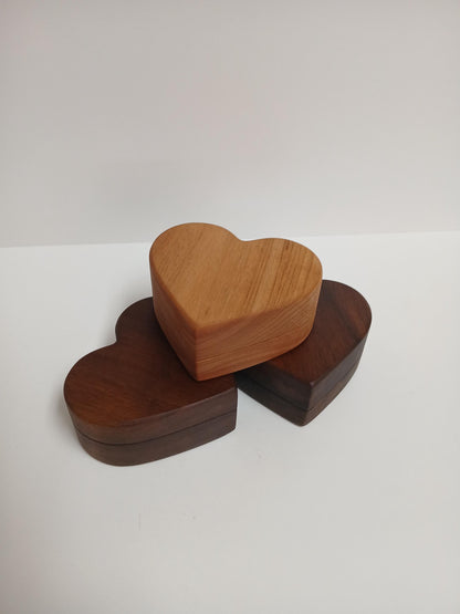 Three wooden heart-shaped boxes of different species including alder and dark walnut on a white background